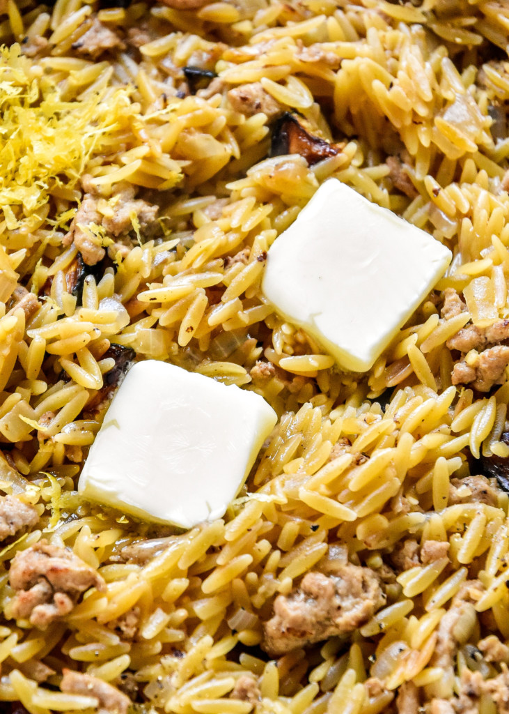 butter melting on top of the pan of ground turkey zucchini orzotto.