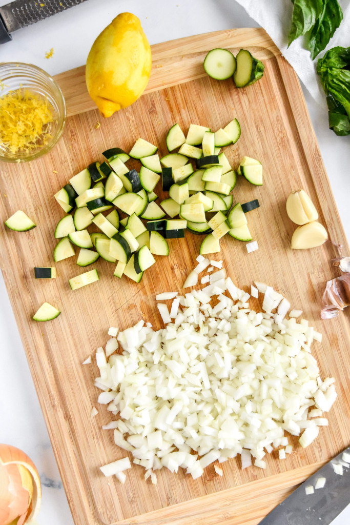 chopped onion and zucchini on a cutting board.