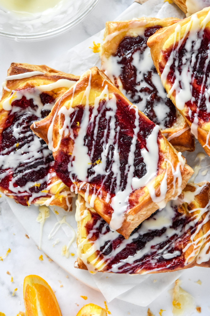a pile of leftover cranberry sauce cheese danish with orange icing drizzled on top.