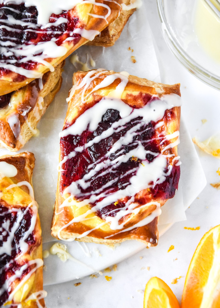 Leftover cranberry sauce cheese danish with icing on a white cutting board.