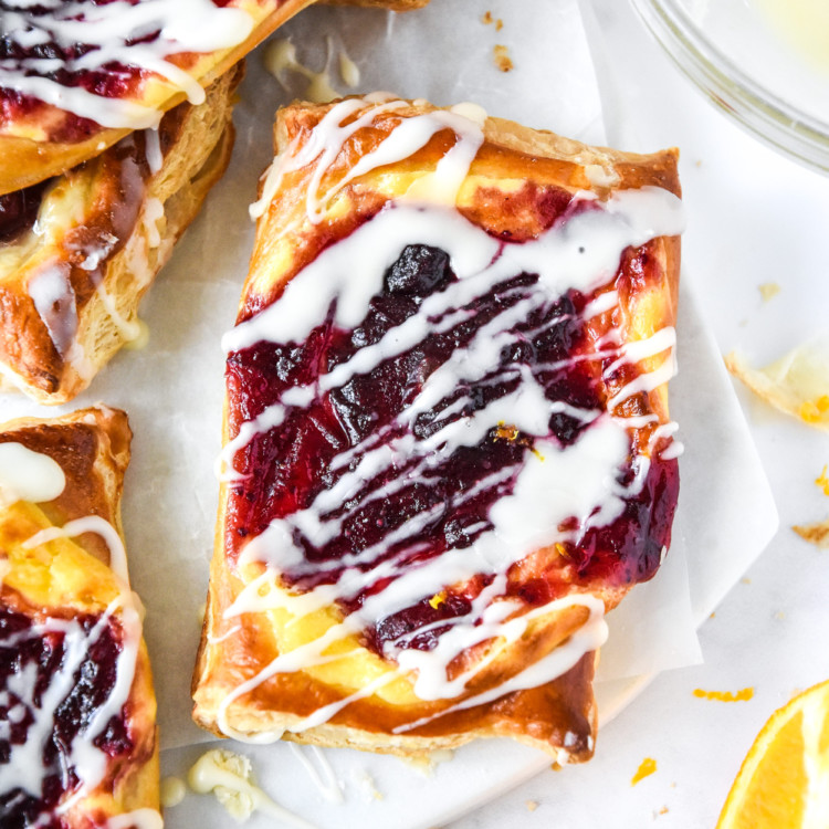 Leftover cranberry sauce cheese danish with icing on a white cutting board.
