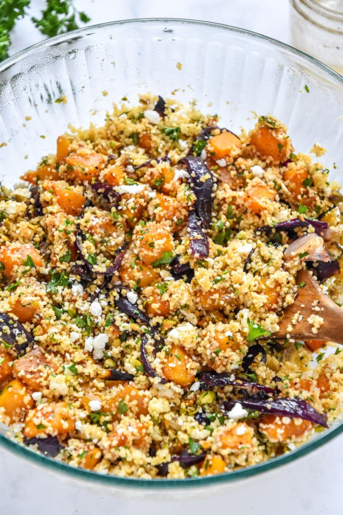 all ingredients for the roasted butternut squash salad mixed together in a glass bowl.