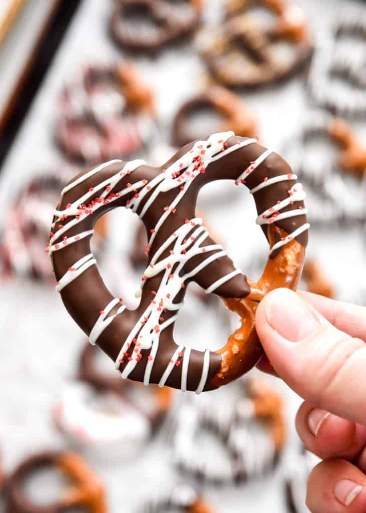 homemade chocolate dipped pretzel with drizzle white chocolate and red sprinkles.