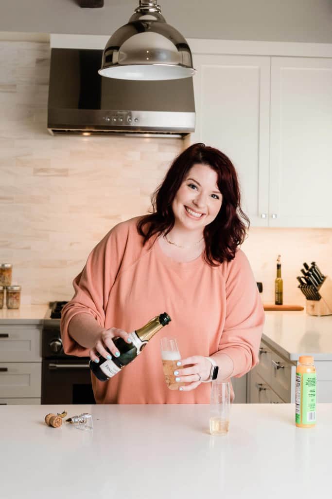 brown haired woman pouring champagne into a glass.