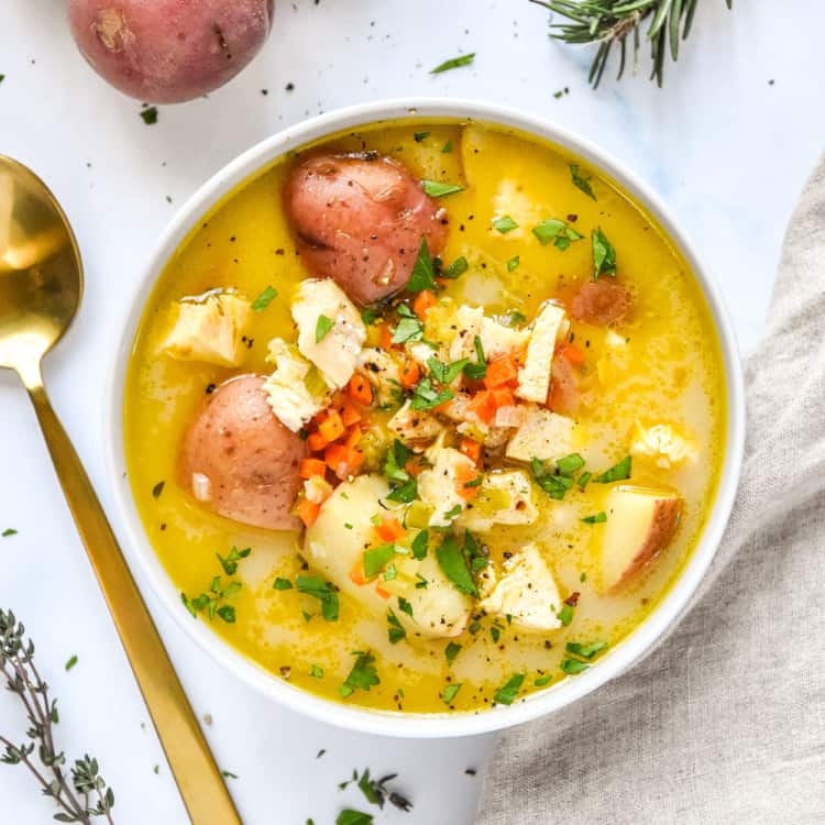 simple red potato chicken soup in a bowl on a white table.