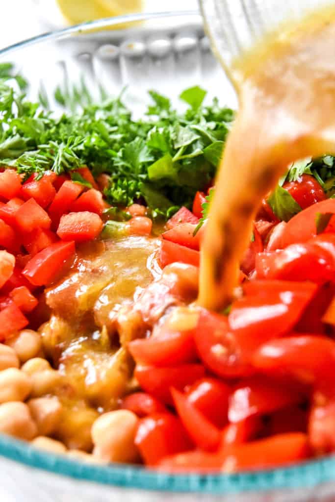 pouring dressing on the make-ahead vegan chickpea salad.