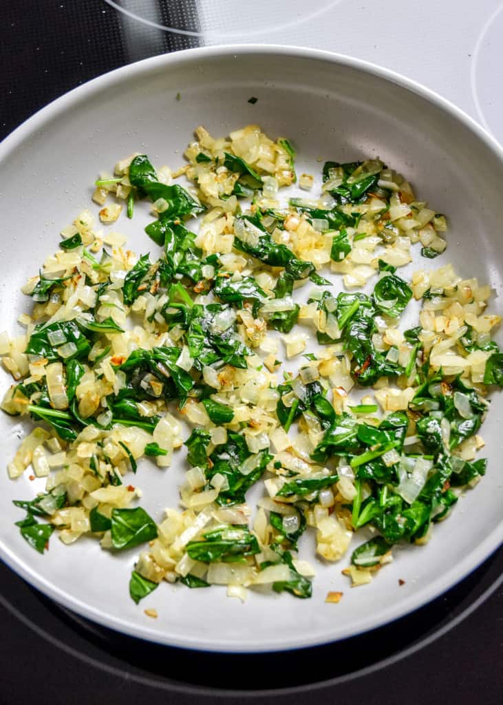 cooked spinach and onions in a skillet to make filling for the stuffed chicken breast.