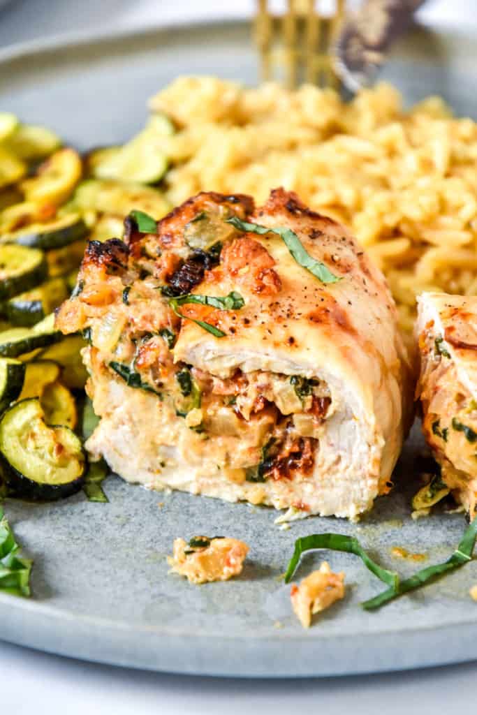 air fryer stuffed chicken breast on a plate cut in half.