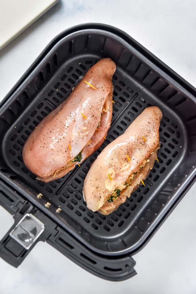 raw stuffed chicken breasts in the air fryer before cooking.