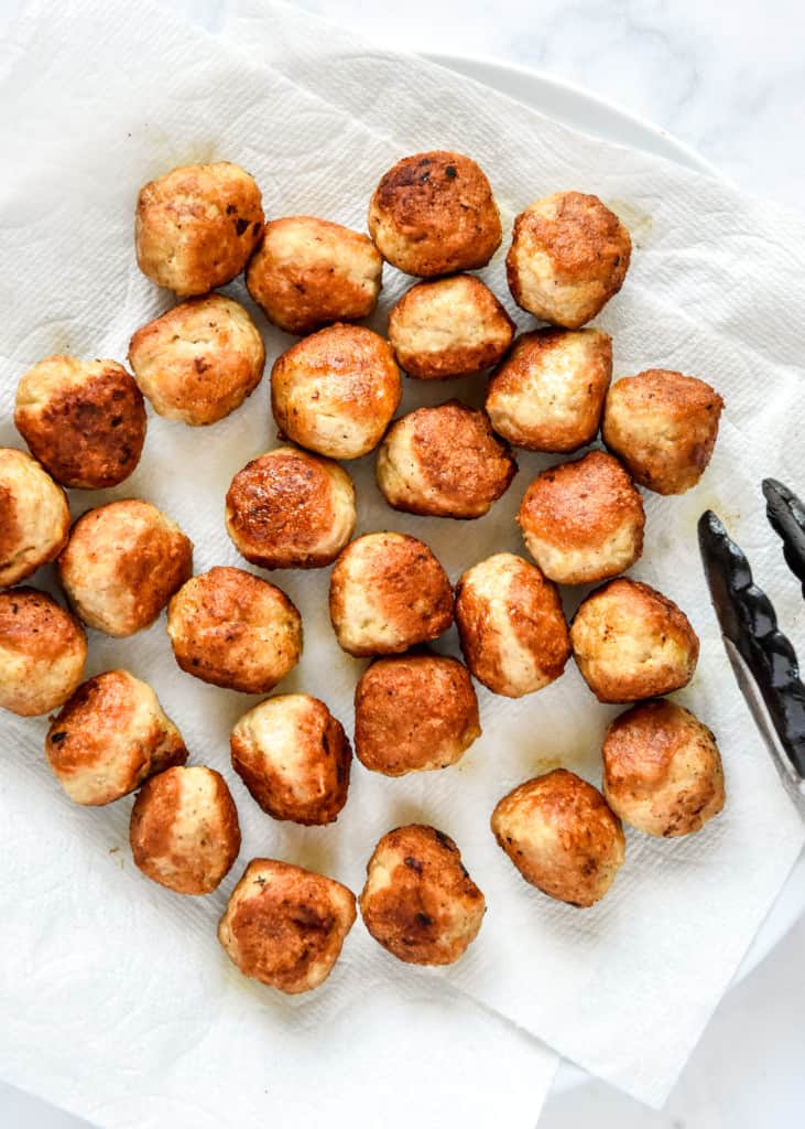 cooked ground turkey meatballs on a paper towel lined plate.