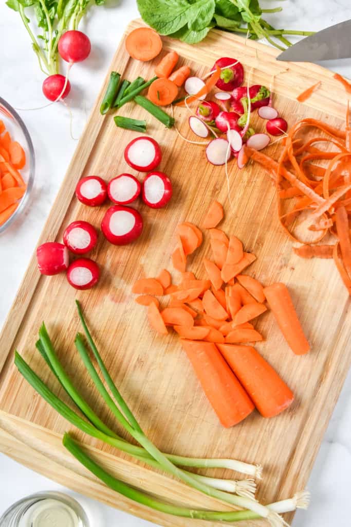 slicing and peeling the carrots and radishes for the pickled veggie salad.