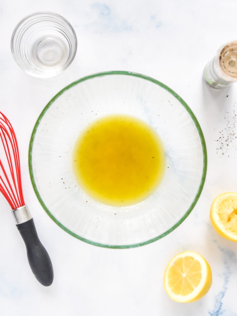 lemon oil dressing in a large glass bowl for the make-ahead quinoa party salad.