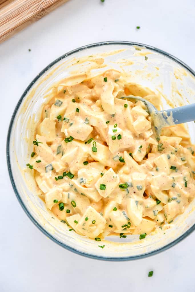 bowl of freshly mixed up easy deviled egg salad with chopped chives on top.