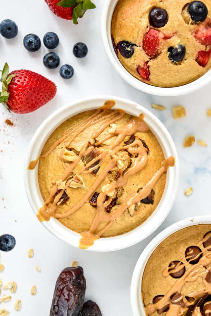 Individual air fryer baked oats in a white ramekin with peanut butter drizzled on top.