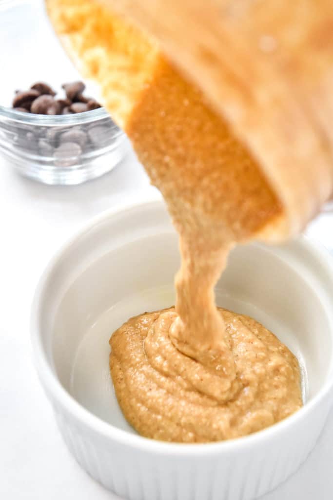 pouring batter into a greased white ramekin.