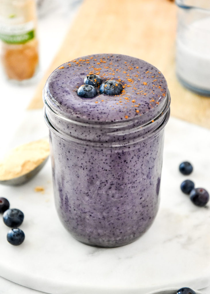 peanut butter powder blueberry cinnamon smoothie in a glass mason jar.