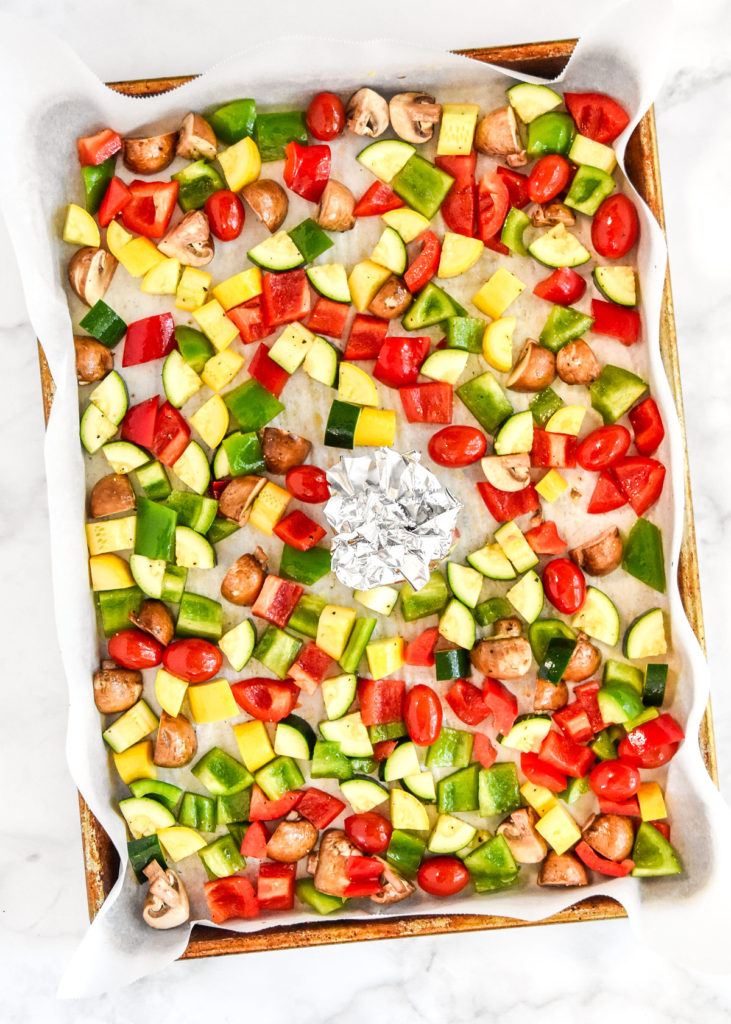 raw veggies on a baking pan with oil and salt before roasting.