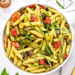 roasted veggie pesto pasta salad in a bowl with basil on top.