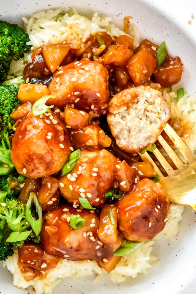 homemade pineapple teriyaki chicken meatballs with broccoli over rice with one half eaten meatball.