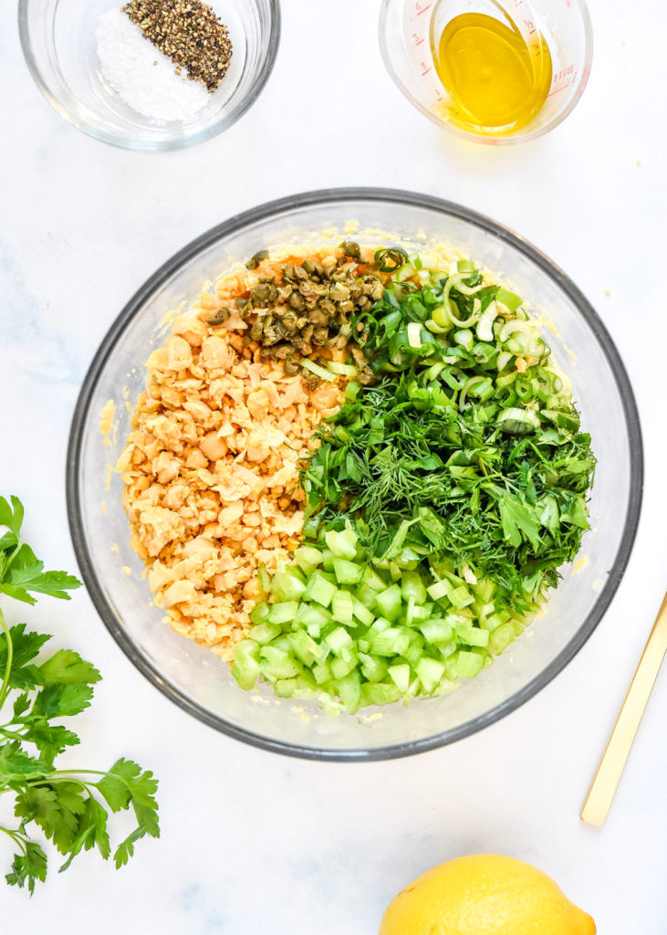 ingredients for the herby lemon mashed chickpea salad all chopped in a glass bowl.
