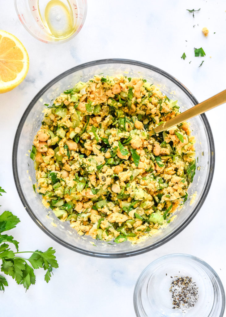 finished herby lemon mashed chickpea salad in a glass bowl with fresh herbs and lemon juice.