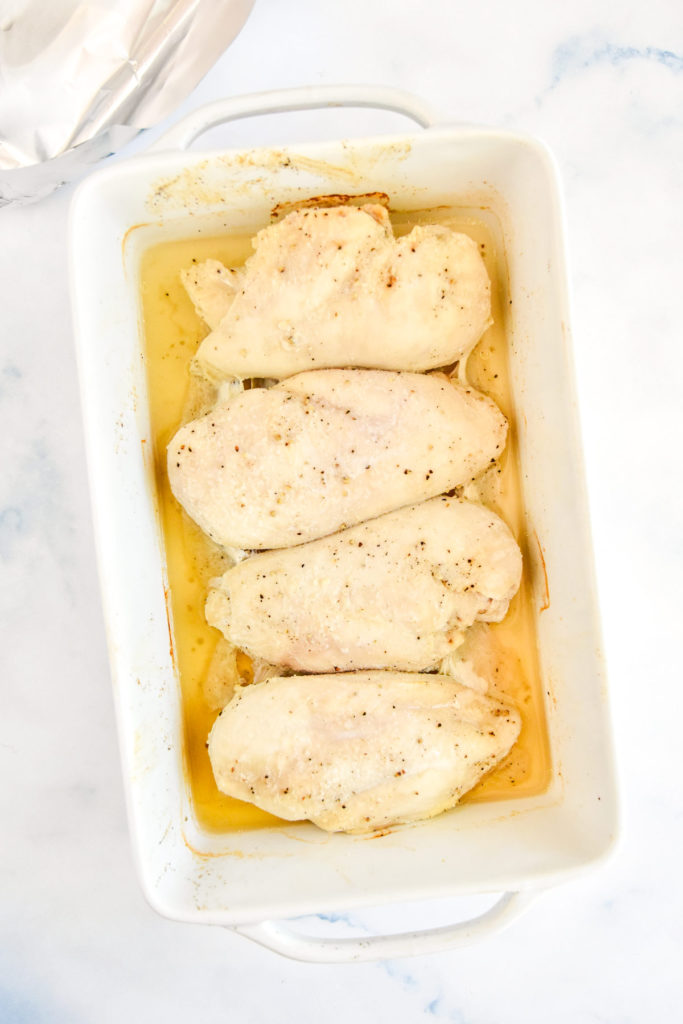 a white pan of baked chicken breasts whole.