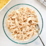 baked shredded chicken breast in a glass bowl with a large fork.