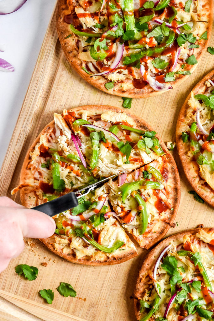 cutting the barbecue chicken flatbread pizzas with a pizza cutter.