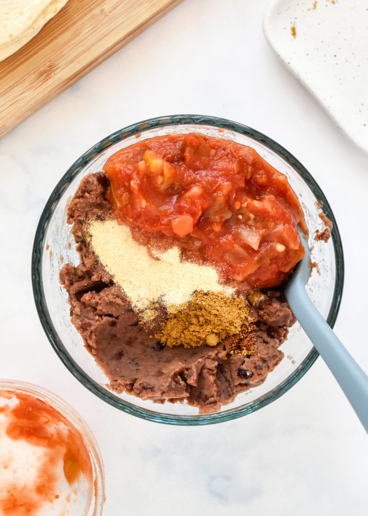 beans and salsa in a glass bowl with a spoon.