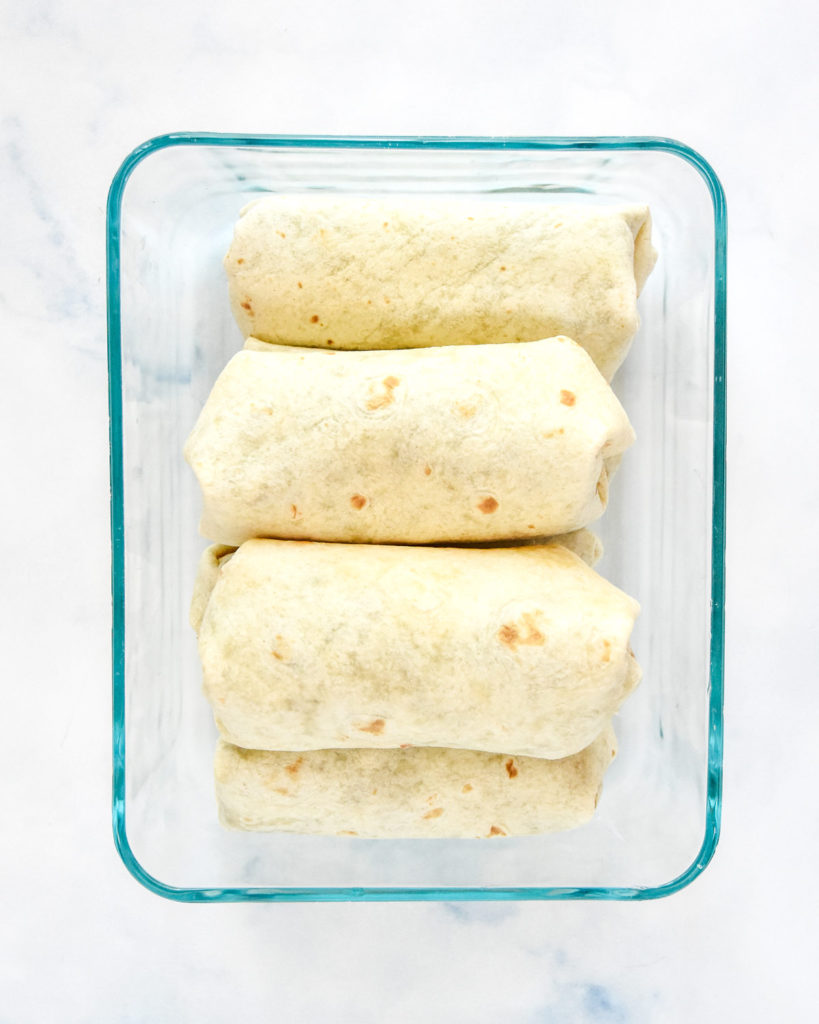 wrapped burritos in a glass meal prep container.