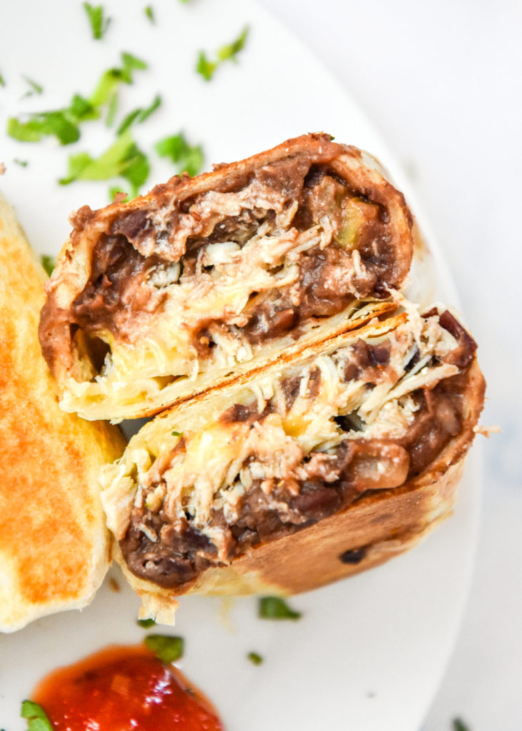 an easy chicken bean burrito meal prep cut in half to show interior of burrito.