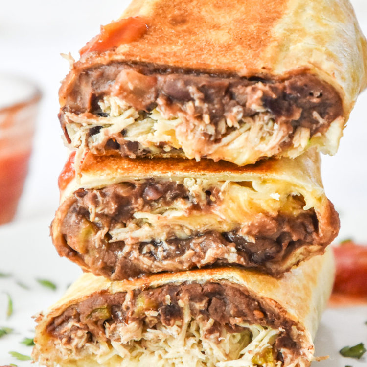 easy chicken bean burritos cut in half and stacked on a plate.