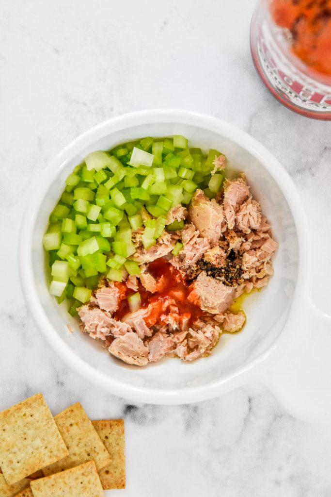 tuna celery buffalo sauce and oil in a bowl with tuna before mixing up.