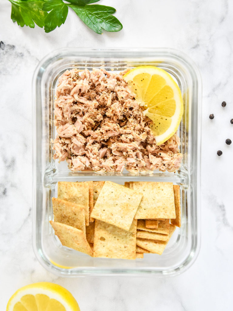 lemon pepper tuna with crackers in a glass meal prep container.