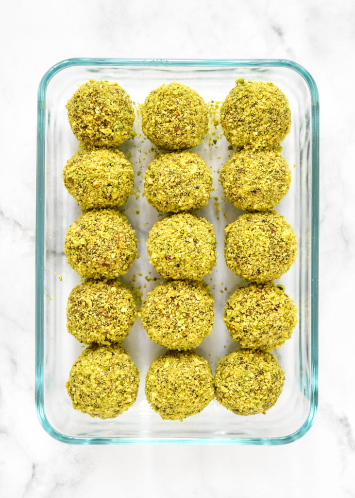 pistachio date energy balls in a rectangular glass meal prep container.