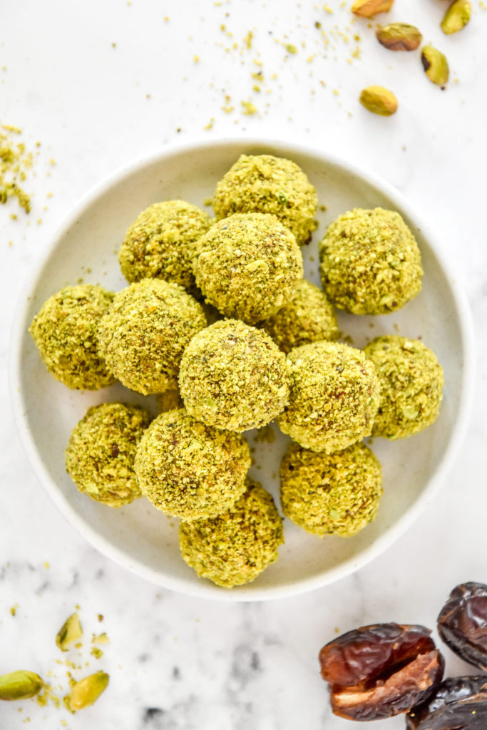 Pistachio Date Energy Balls with green coating on a white plate.