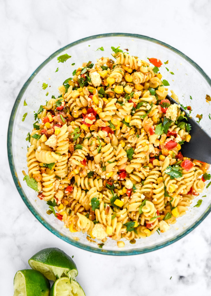 a bowl of mixed pan roasted corn pasta salad with a spoon.