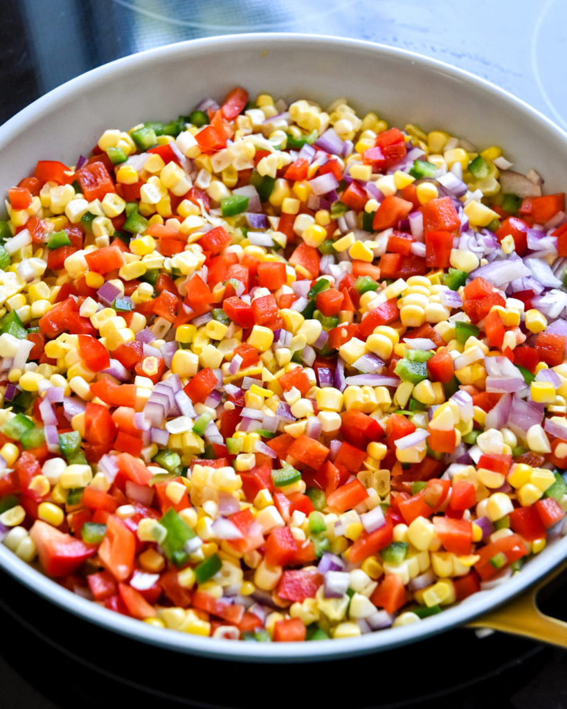 a pan of fresh corn, peppers and onions before cooking.