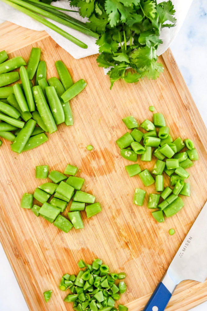 cutting sugar snap peas on a cutting board.
