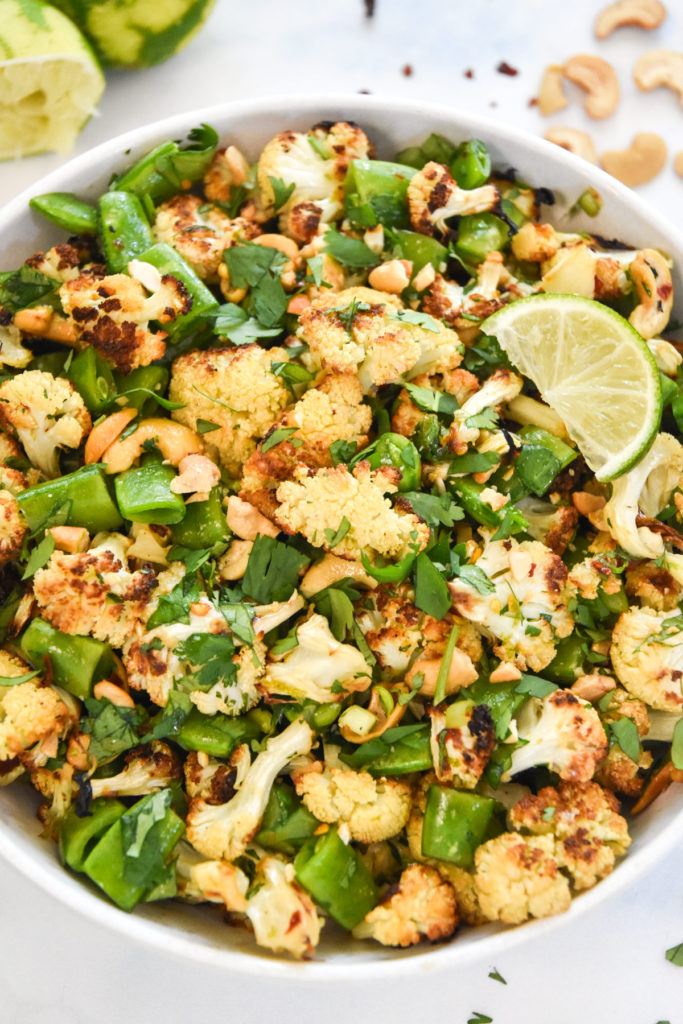 chili lime roasted cauliflower salad in a bowl with cilantro and cashews on top.